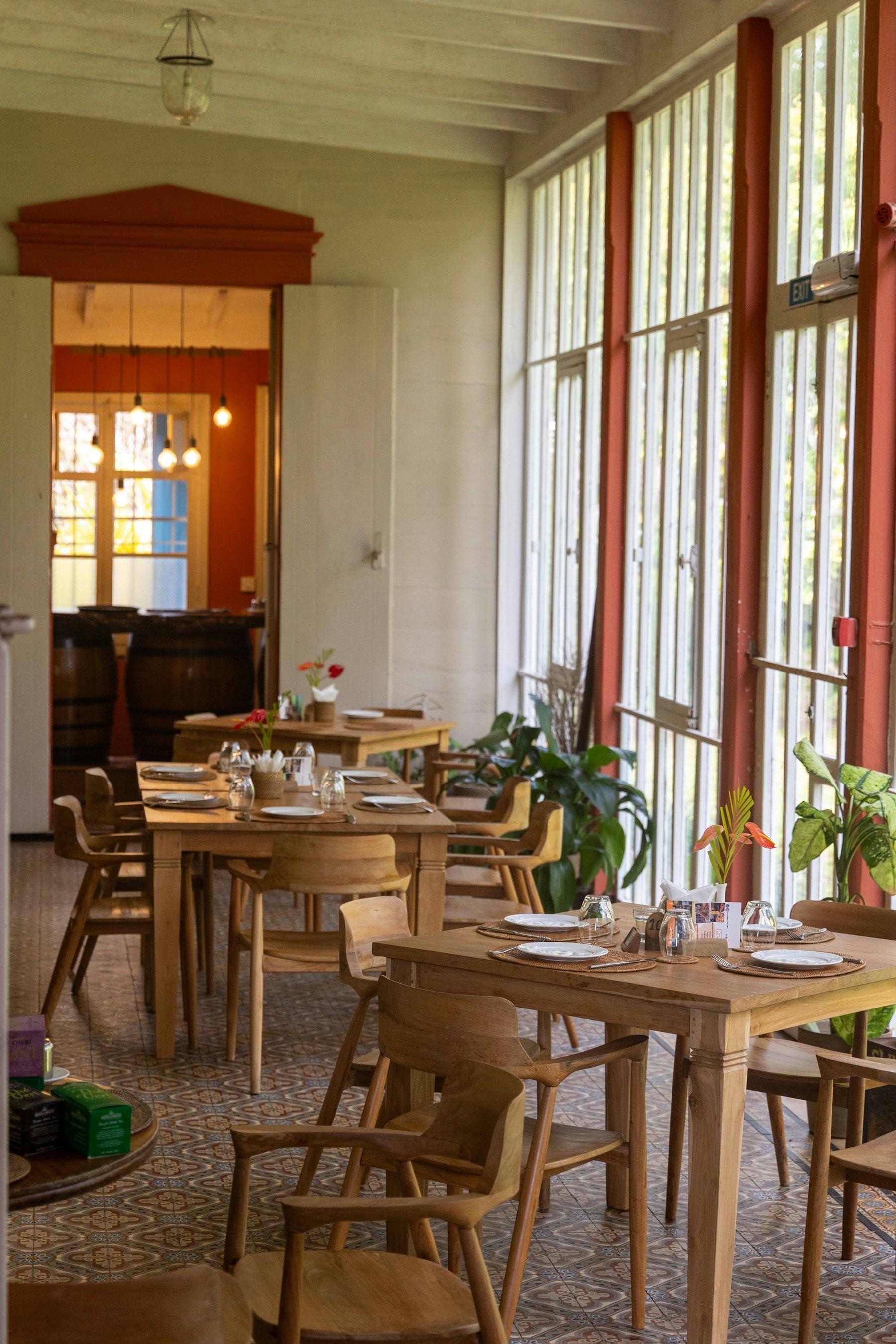A sunlit wooden dining room, tables laid for service